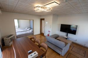 a living room with a table and a television and a bed at Seaside Deer Shiraoi in Shiraoi