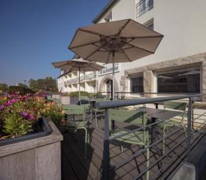 a patio with a table and chairs and an umbrella at Hôtel La Résidence in Roscoff