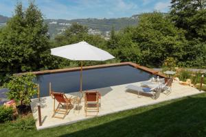 a swimming pool with an umbrella and a table and chairs at Casa in Bioedilizia con Bio Piscina Naturale – Ai Due Gelsi in Grancona
