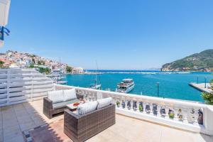a balcony with wicker chairs and a table and a view of the water at Adonis Rooms in Skopelos Town