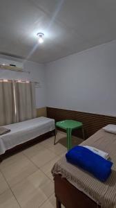 a room with two beds and a green table at Hotel Gramados in Porangatu +12 photos