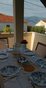 a table with plates and utensils sitting on top of a balcony at Bila Lumbrela in Supetar