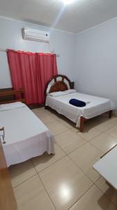 a bedroom with two beds and a red curtain at Hotel Gramados in Porangatu