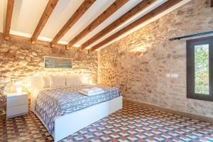 a bedroom with a bed in a stone wall at Casa Es Putxet in Cala Ratjada +25 photos