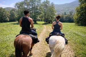 two people riding on horses down a dirt road at Camping le Rural- 3 étoiles in Tibiran-Jaunac