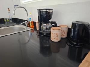 a coffee maker and two cups on a counter at Zion in Capesterre