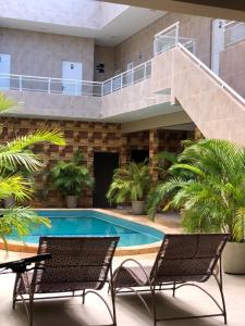 a swimming pool with two chairs and a staircase at Pousada Garrida in Itarema