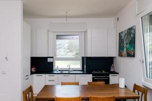 a kitchen with white cabinets and a wooden table at Villa SOL Lago di Endine in Ranzanico