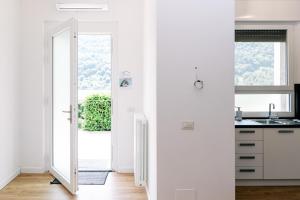 a white kitchen with a door leading to a balcony at Villa SOL Lago di Endine in Ranzanico +110 photos