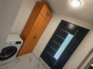 a bathroom with a door and a washer and dryer at Apartma Alpine Gateway in Komenda