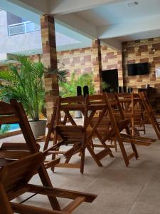a group of wooden tables and chairs in a room at Pousada Garrida in Itarema