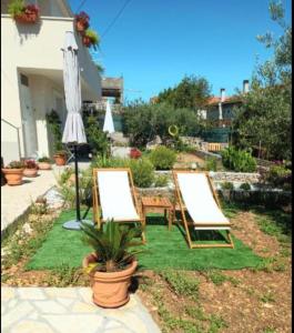 two empty chairs and an umbrella in a yard at Bila Lumbrela in Supetar