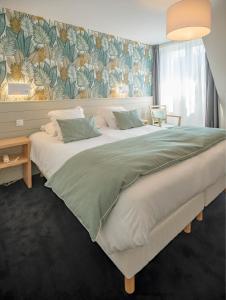 a bedroom with a large white bed with a floral wallpaper at Hôtel La Résidence in Roscoff