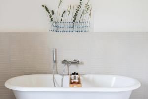 a white bath tub in a bathroom with a vase at La Bastide du Mourre - Fontenille Collection in Oppède +27 photos