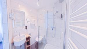 a white bathroom with a sink and a shower at Hotel Villa Sulmana in Neckarsulm