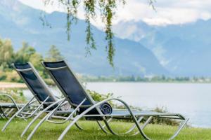 Zwei Stühle stehen im Gras neben einem See in der Unterkunft Familotel Amiamo in Zell am See + 127 Fotos