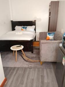 a bedroom with a bed and a couch and a table at Luxe-homestay 1 Bed Executive Studio in Eldoret