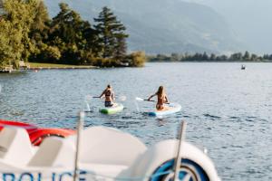 Drei Mädchen sind auf Stand-Up-Paddle-Boards auf einem See unterwegs. in der Unterkunft Familotel Amiamo in Zell am See