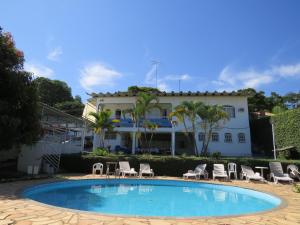 a pool with chairs and a building in the background at Hotel Nuar in Betim