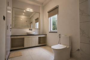 a bathroom with a toilet and a sink and a mirror at Anuttara Retreat in Narendranagar