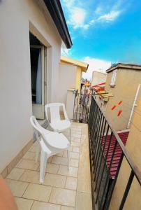 a balcony with two white chairs on a building at La Quiete in Scilla