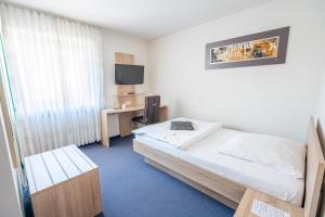 a bedroom with a bed and a desk and a television at Hotel Villa Sulmana in Neckarsulm +14 photos