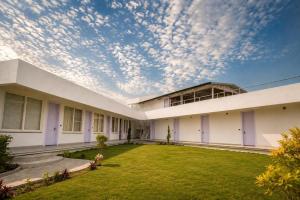 a large white building with a grass yard at Anuttara Retreat in Narendranagar