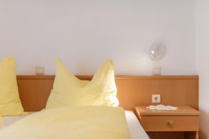a bed with yellow pillows and a clock on the wall at Micheli Hermann Obst- und Weinbauernhof mit "Südtirol Alto Adige Guest Pass - Mobilcard" in Caldaro