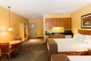 a hotel room with two beds and a table and a kitchen at Hôtel St-Bernard in St-Bernard de Lacolle +16 photos