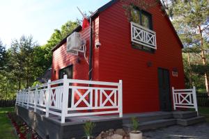a red house with a white fence in front of it at Mazury Czerwony Domek Jacuzzi in Romany