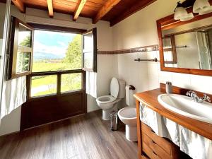 a bathroom with a toilet and a sink and a window at El Balcón Del Profesor in Cereceda