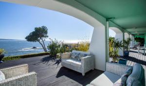 an outdoor patio with a chair and the ocean at Sea view Luxury Apartment in Paço de Arcos