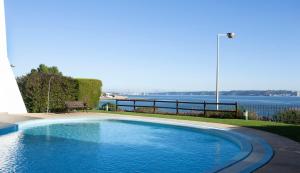 a swimming pool with a view of the water at Sea view Luxury Apartment in Paço de Arcos