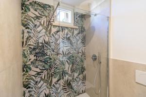 a bathroom with a shower with a tropical print shower curtain at Casa Bortolo in Garda +18 photos