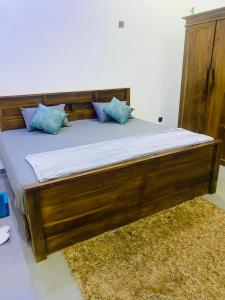 a wooden bed with blue pillows on top of a rug at ZEN House Arugambay in Arugam Bay +10 photos