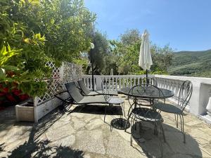 a patio with a table and chairs and an umbrella at Ulivo Liguria With pool in Gazzelli