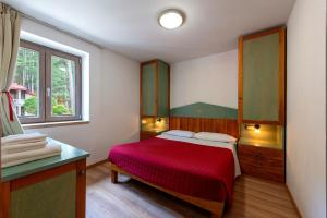 a bedroom with a red bed and a window at Residenza Lorica in Lorica