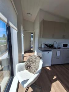 a kitchen with a white chair with a blanket on it at Hólmahjáleiga Guesthouse in Hvolsvöllur +32 photos