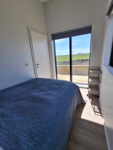 a bedroom with a blue bed and a large window at Hólmahjáleiga Guesthouse in Hvolsvöllur