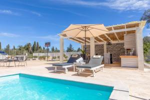 a pool with two lounge chairs and an umbrella at Villa Elegio in Kavos