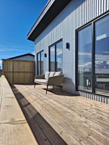a couch sitting on a deck next to a building at Hólmahjáleiga Guesthouse in Hvolsvöllur