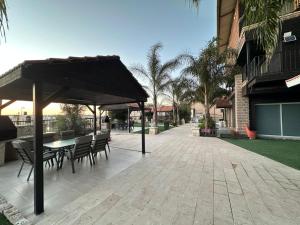 a patio with a table and chairs and an umbrella at carmel cabins suite nu 9 in Yājur