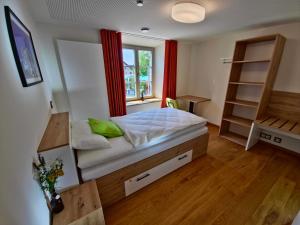 ein Schlafzimmer mit einem Bett und einem Fenster mit roten Vorhängen in der Unterkunft Hotel im Sud in Eggenfelden