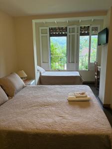 two beds in a room with two towels on a bed at Pousada 14 Bis in Petrópolis