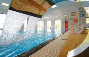 a swimming pool with a water slide in a building at Hotel i Apartamenty Gorzelanny Dźwirzyno in Dźwirzyno