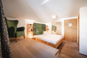 a bedroom with a bed and a green chair at Genusshotel Fichtenhof in Grossarl