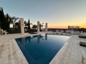 a swimming pool with chairs and a sunset in the background at carmel cabins suite nu 10 in Haifa