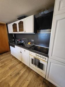 a kitchen with white cabinets and a stove top oven at Worker's Home by Nina in Herzberg am Harz +6 photos