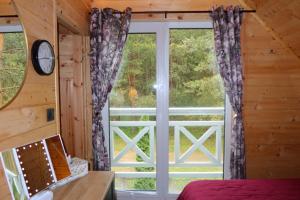 a bedroom with a large window in a cabin at Mazury Czerwony Domek Jacuzzi in Romany