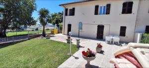 a large white house with a yard with chairs and flowers at Casa vacanza del Cavallo in Senigallia